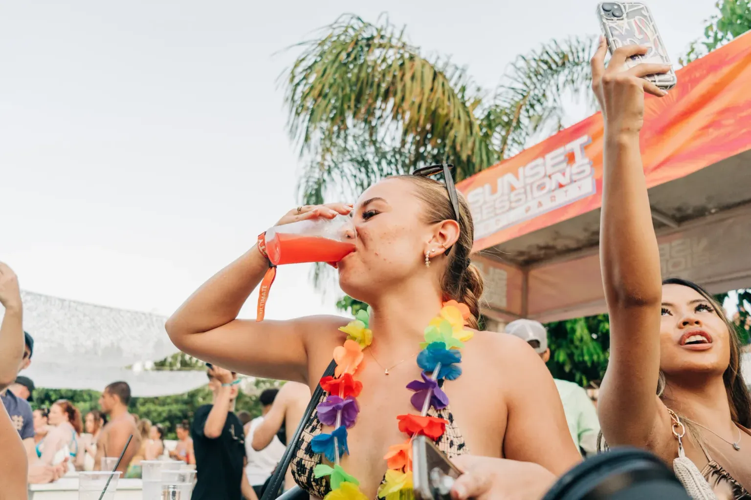 Girl drinking from a cup while partying beside the pool at Sunset Sessions Pool Party in Ayia Napa during the day