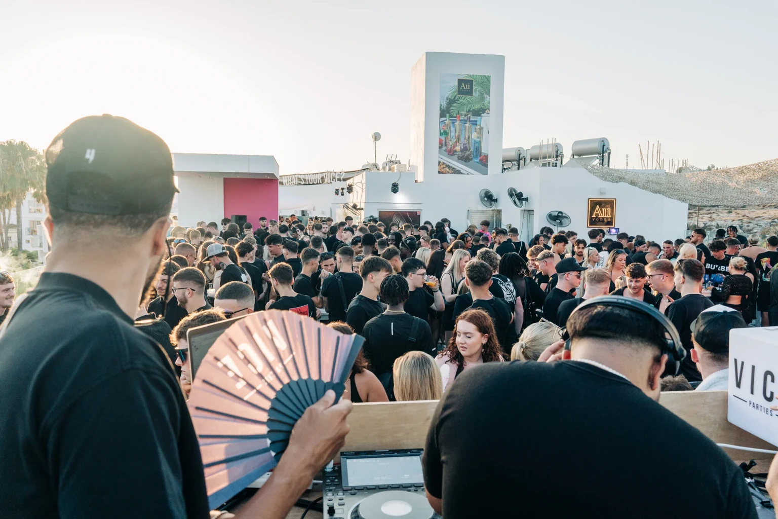 DJ overlooking a packed rooftop crowd at the Vice Rooftop Party in Ayia Napa during a bright summer sunset
