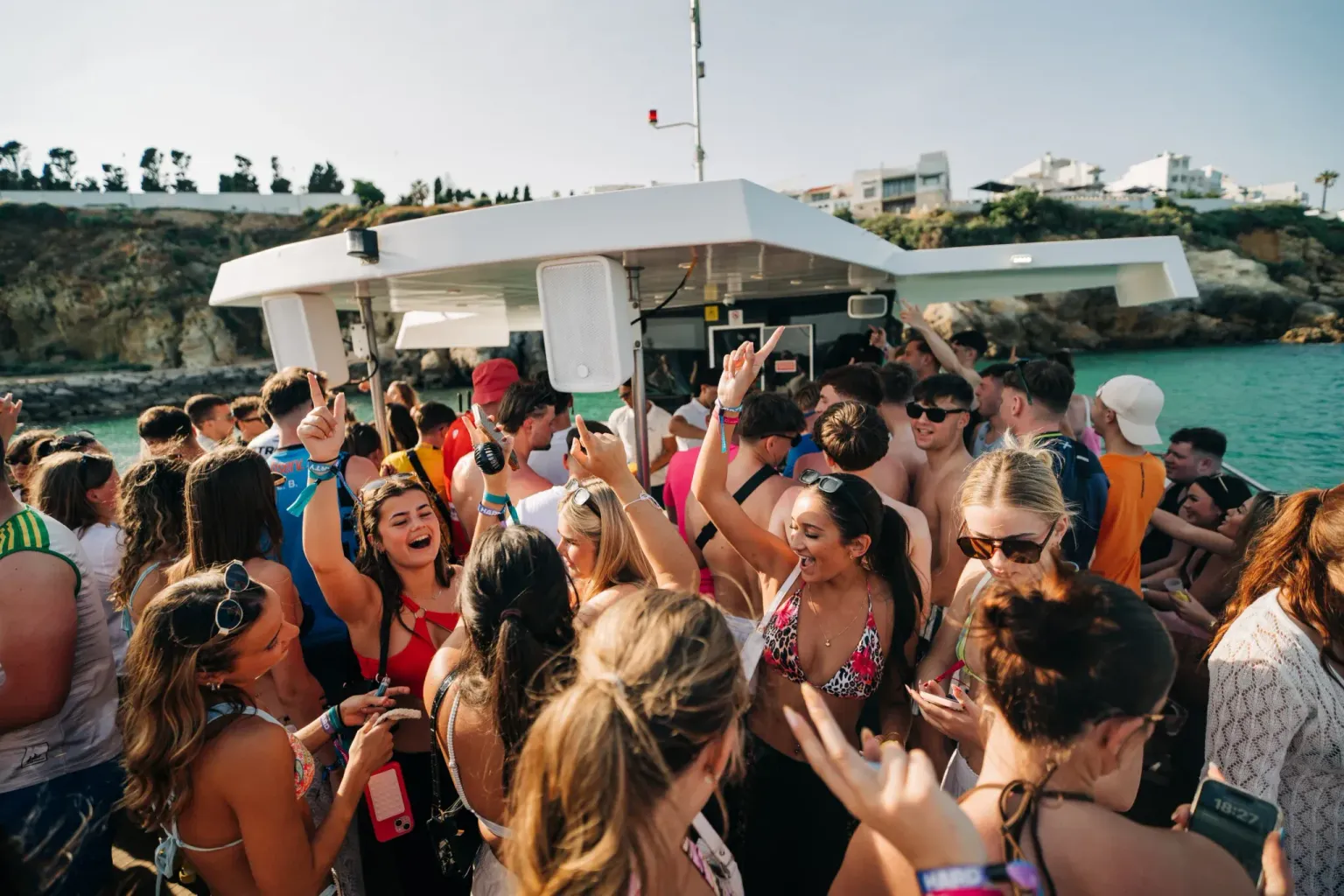 Girls and lads partying on deck at the Albufeira Boat Party in Albufeira, dancing and enjoying drinks under the sun with stunning coastline views.