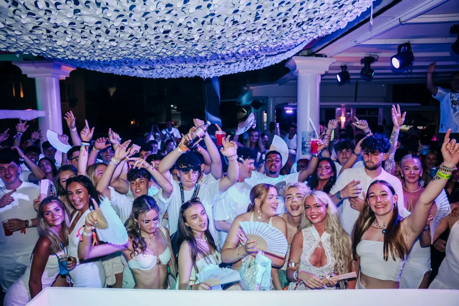 Agenda White Party in Kavos packed wall to wall, hands up, fans waving and drinks flowing under bright club lights