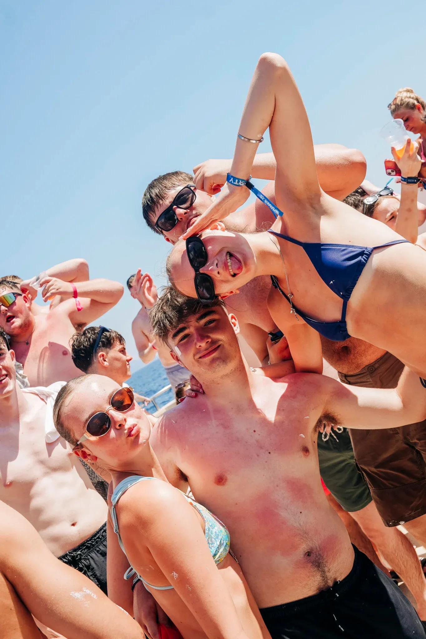Lads and girls pose for the camera on the Kavos Booze Cruise, smiling, pulling faces and fully in party mode at sea