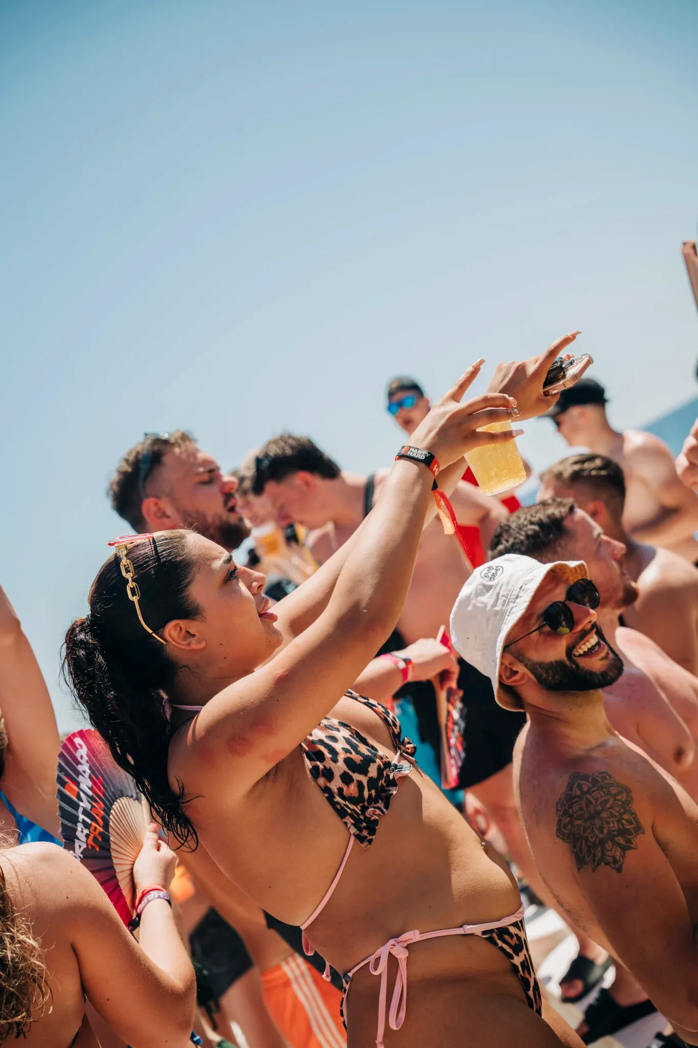 Girls and lads raise drinks and film the madness on the Kavos boat party as the deck party fires up