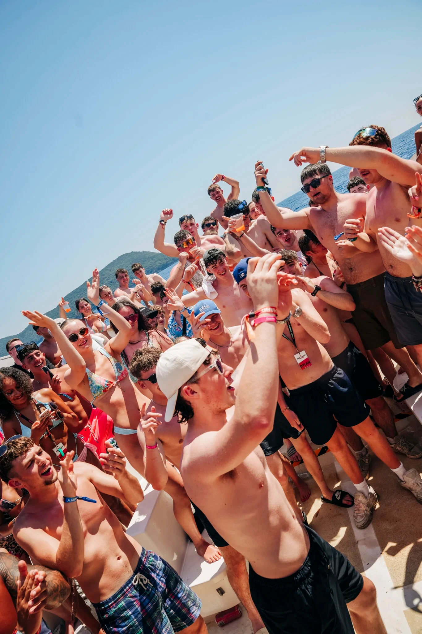 Lads and girls chant and cheer on deck during the Kavos Booze Cruise, drinks raised as the boat party goes full throttle