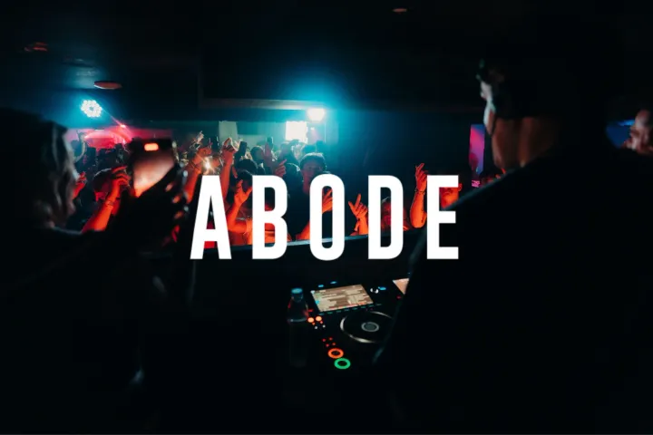 Crowd partying at Ayia Napa Abode event with DJs performing in a packed nightclub atmosphere under red and blue lights