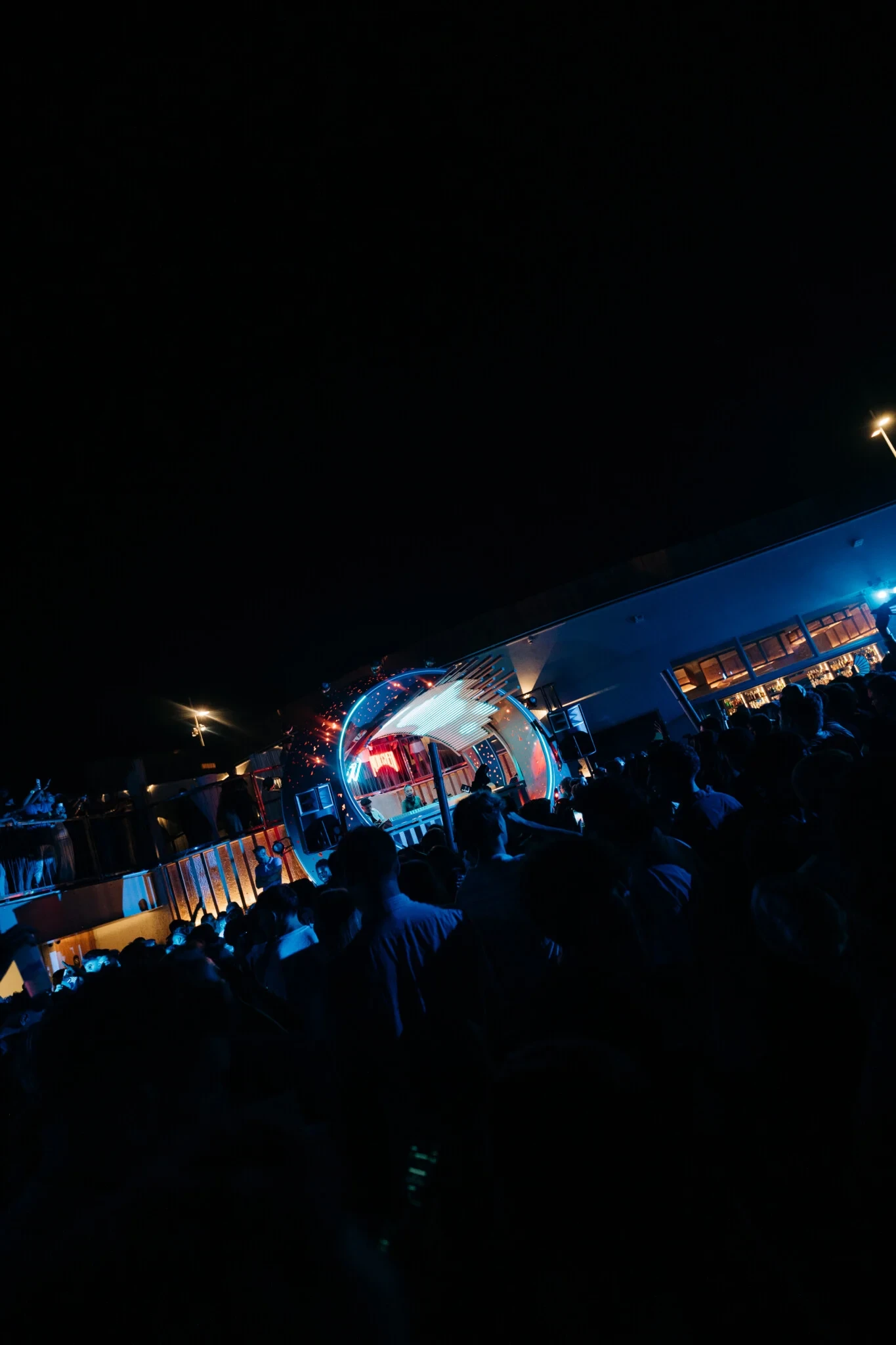 Crowd packed shoulder to shoulder at Cafe Del Mar Malta as neon stage lights fire across the terrace and the DJ booth glows into the night