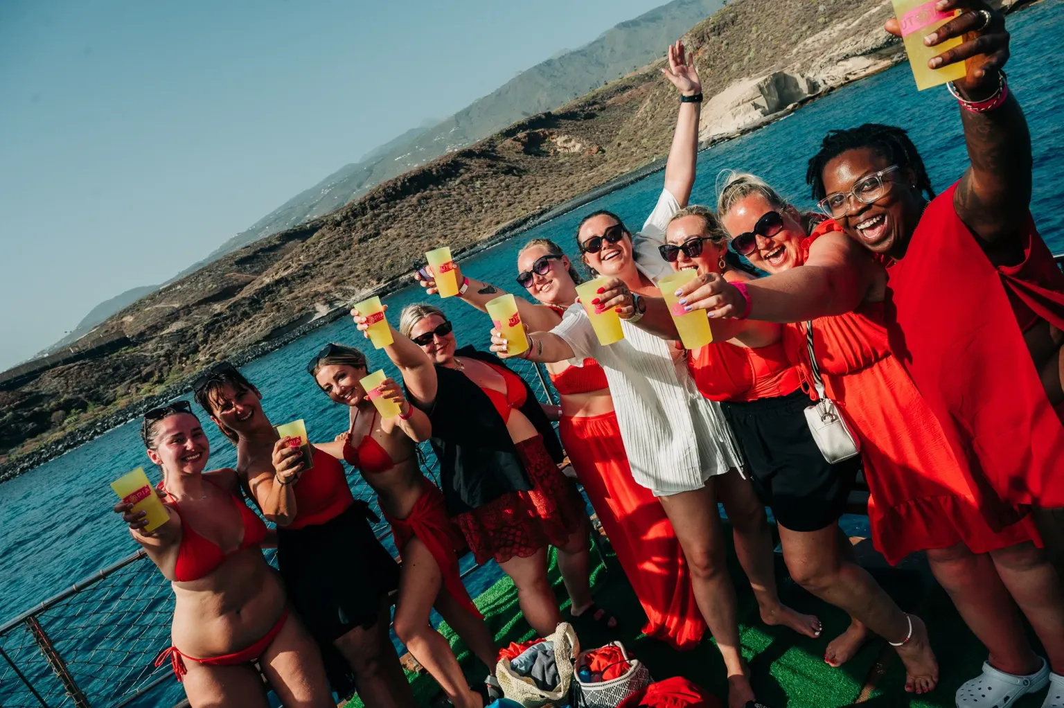 Girls raising drinks on a Tenerife boat party, sunshine out, ocean views and big daytime party energy on deck with the girls lined up