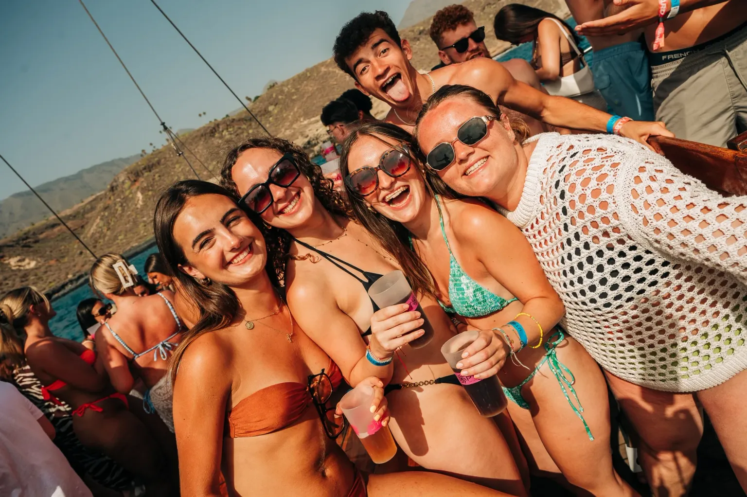 Girls smiling on a Tenerife boat party, drinks in hand, sun blazing, music pumping and full daytime party energy