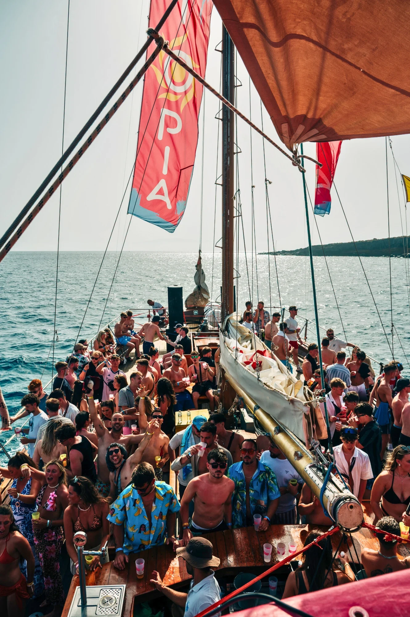Packed Tenerife boat party with lads and girls dancing under UTOPIA flags, drinks up and full daytime chaos on deck