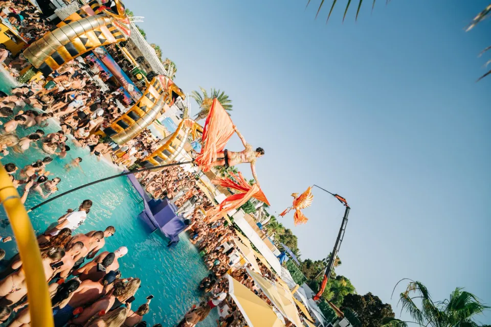 Partygoers dancing beside the pool during an O Beach Ibiza party