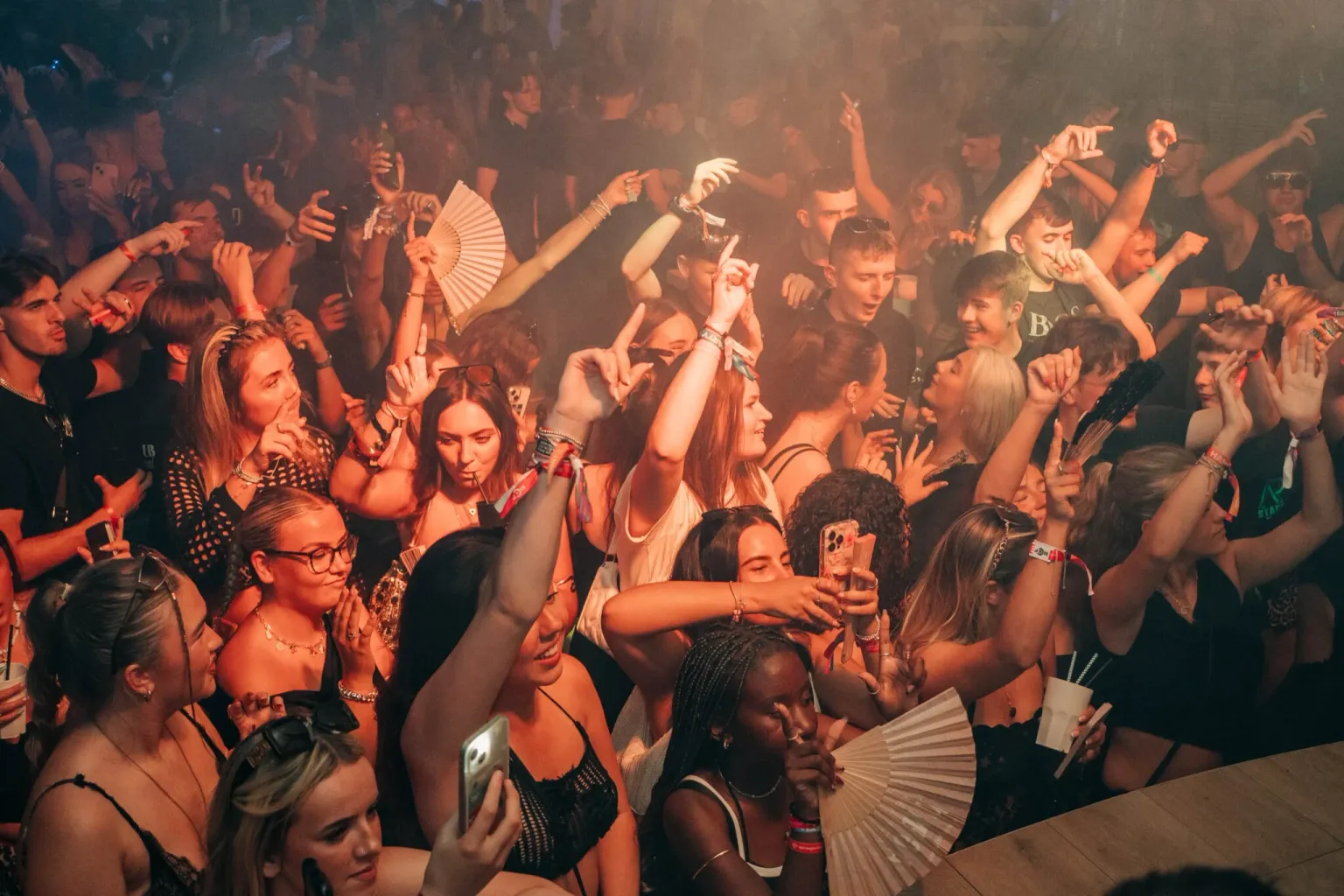 Crowd dancing under orange lights at Agenda Beach Club Party in Magaluf