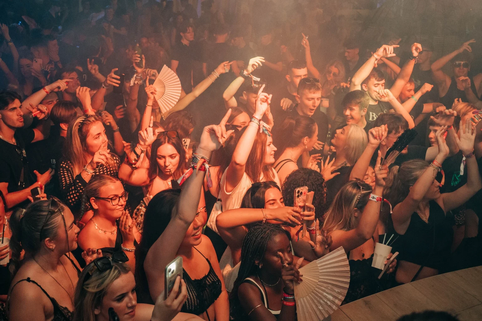 Crowd dancing under orange lights at Agenda Beach Club Party in Magaluf