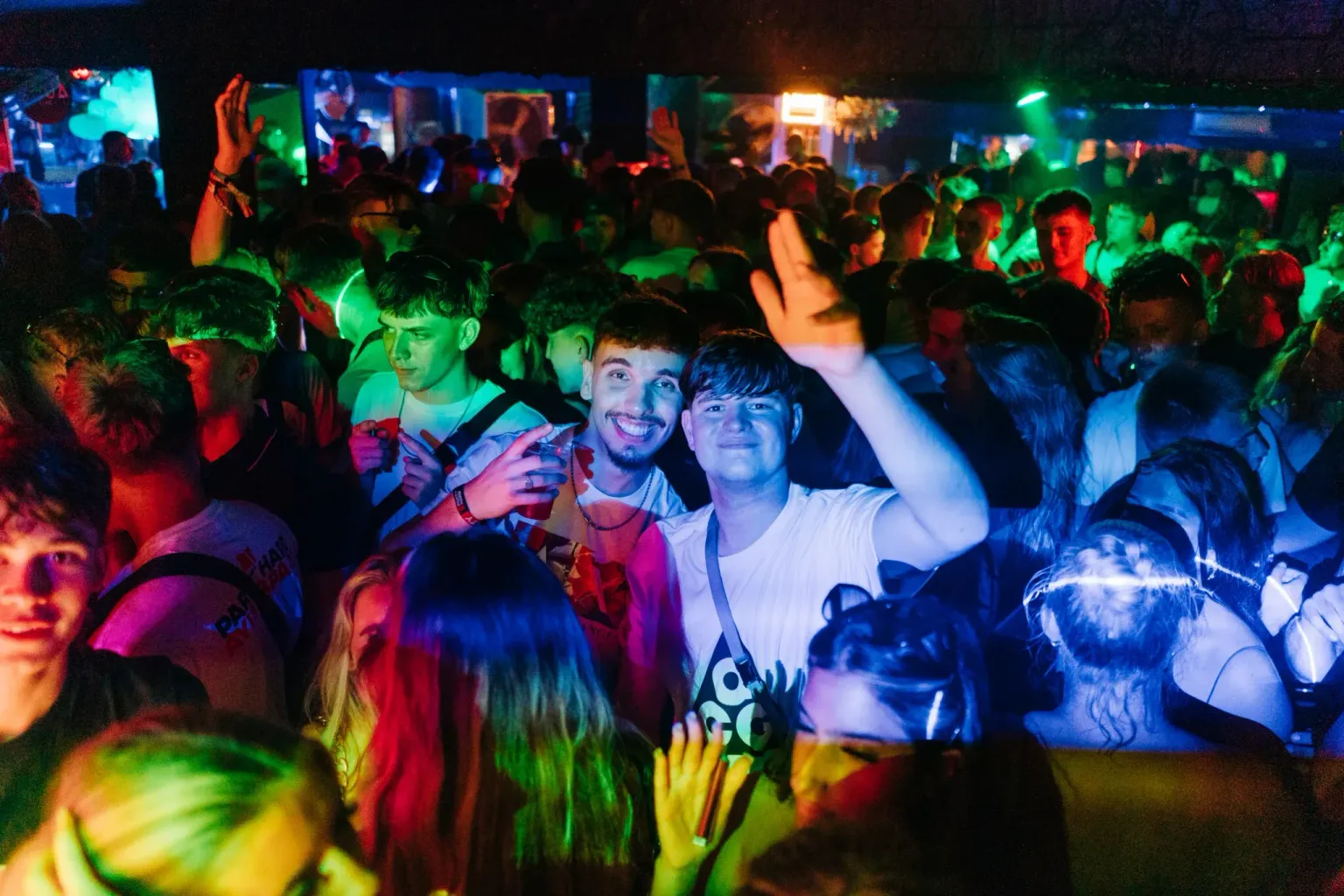 Partygoers dancing under colourful club lighting during the LoveJuice Residency night event in Ayia Napa