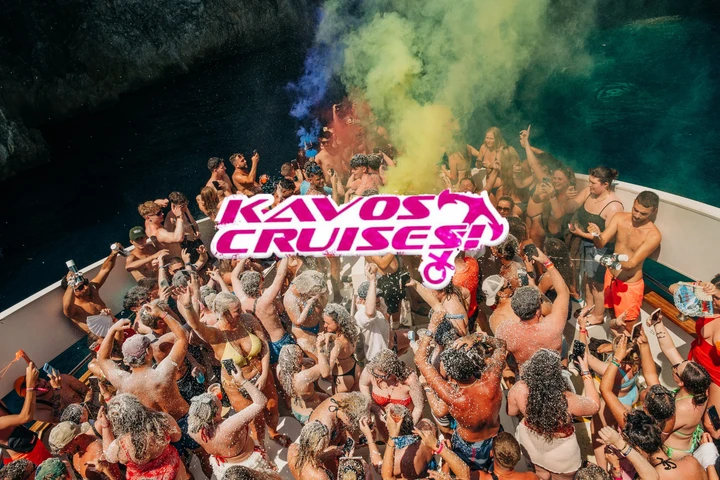 Packed Kavos boat party booze cruise deck covered in foam as the crowd parties under coloured smoke above clear blue water