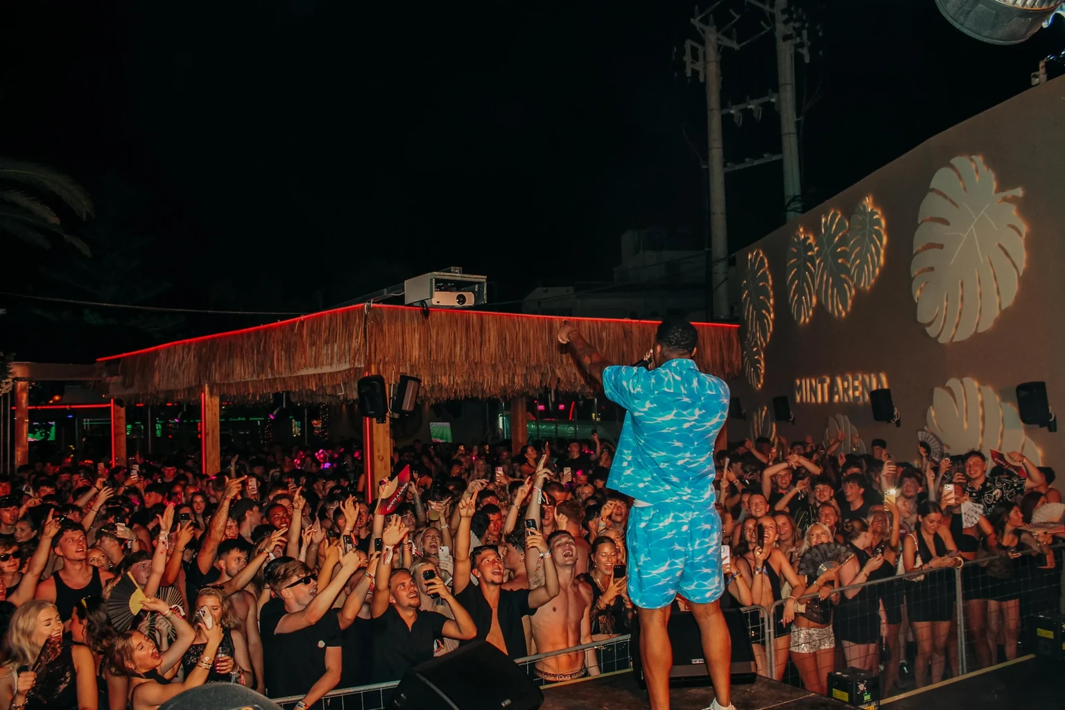 Crowd cheering a performer during a Malia club night