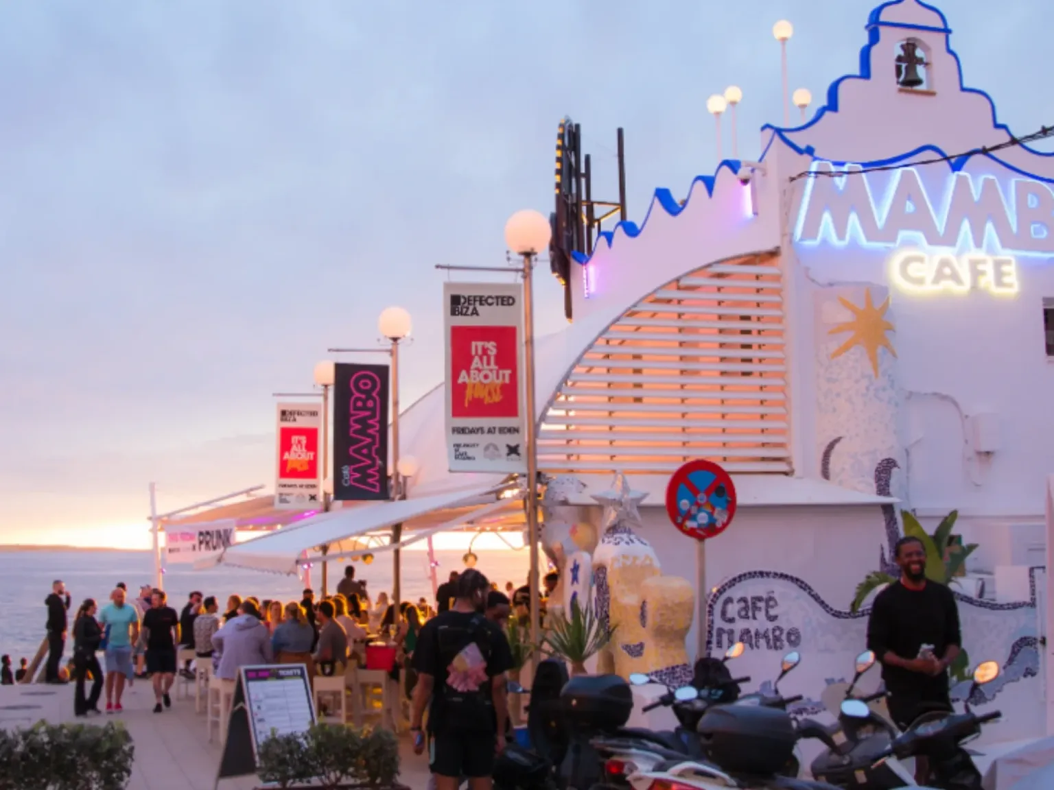 Cafe Mambo Ibiza Bar stree4t v view with neon lights logo at sunset with people sitting and drinking at the bar