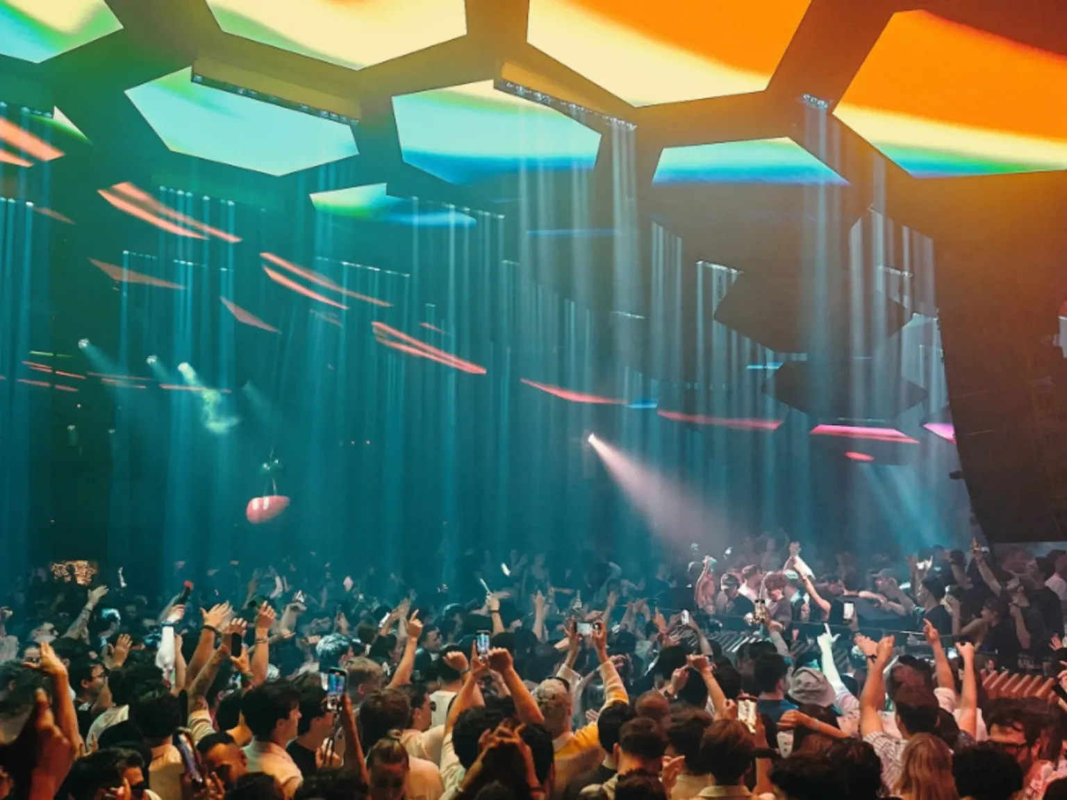 Pacha Ibiza inside crowd view with blue, orange and yellow lighting and a dancing crowd