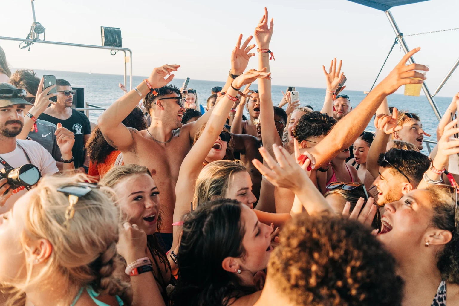 Friends dancing together in a packed crowd on the Fantasy Boat Party off the coast of Ayia Napa in summer