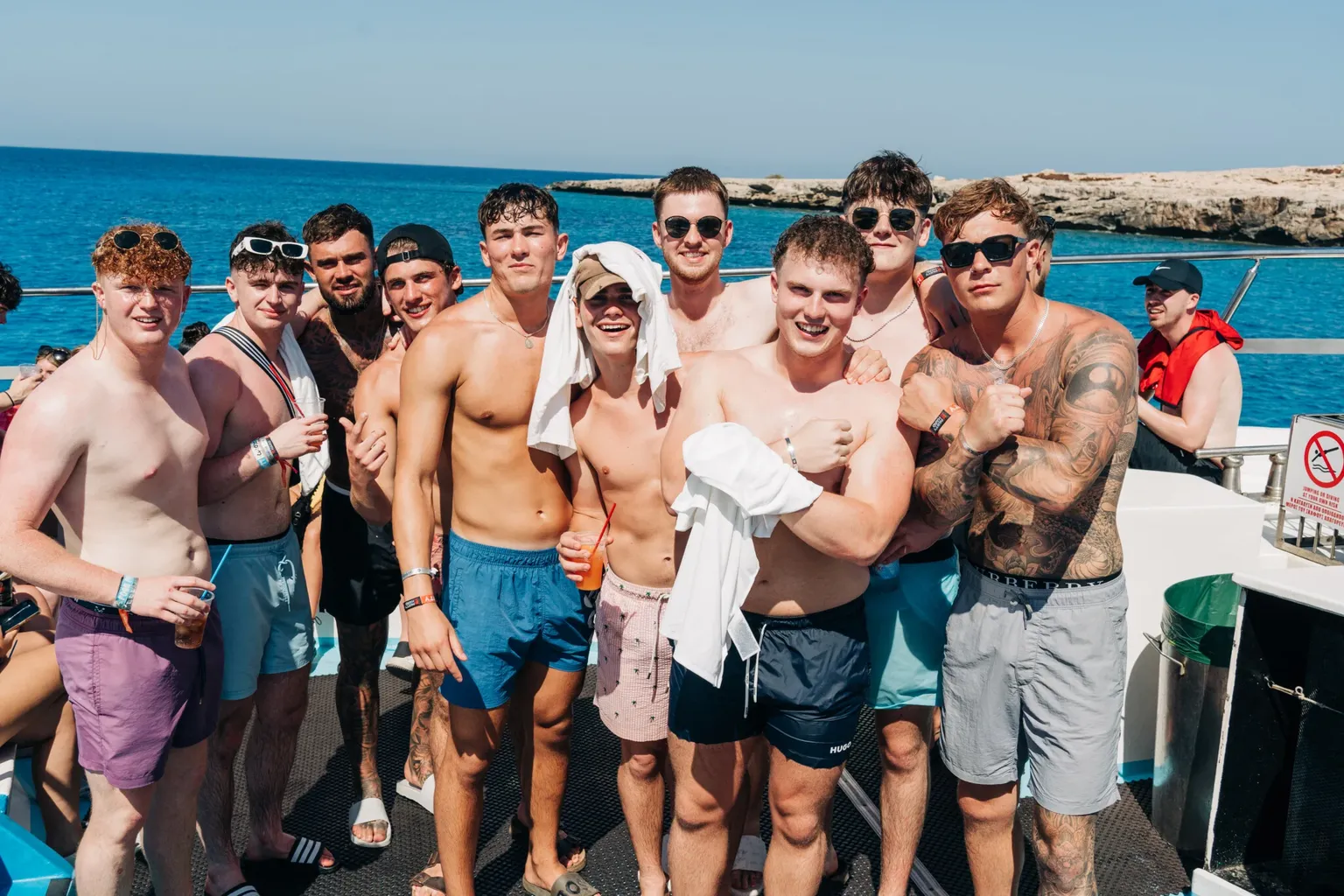 Group of lads posing together on the Fantasy Boat Party with the bright blue Ayia Napa sea behind them